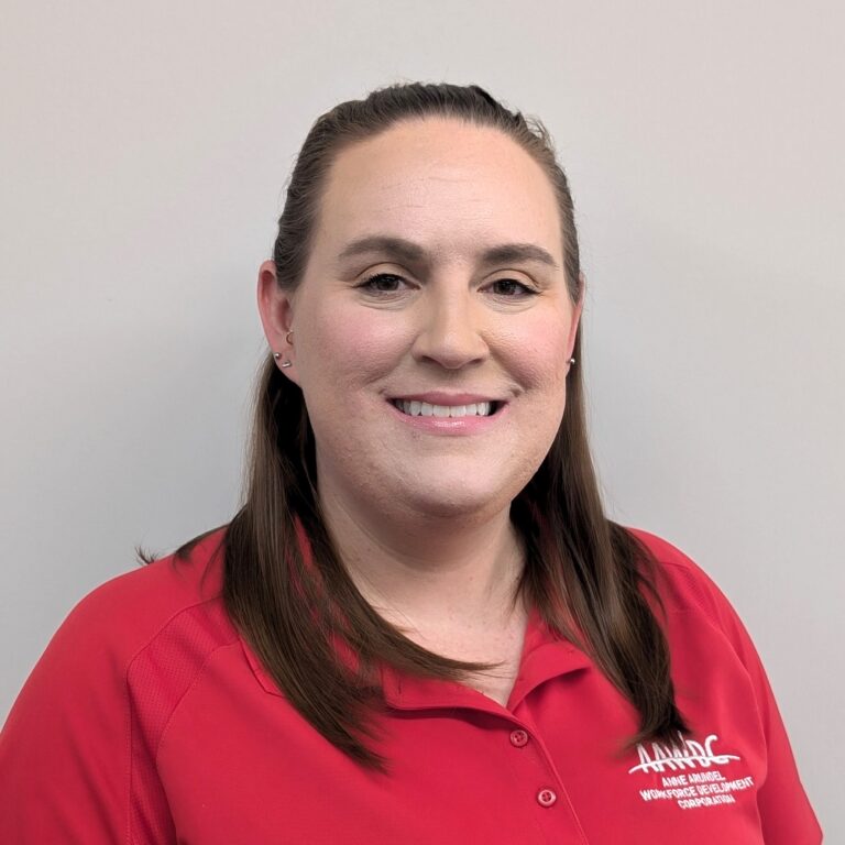 Person smiling in a red AAWDC polo shirt against a plain light background.