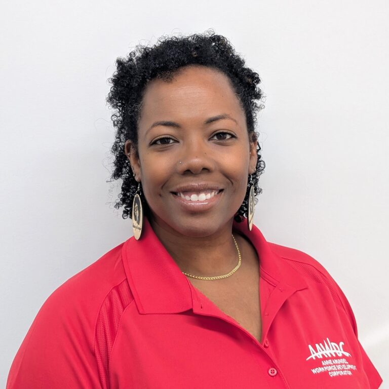 Person smiling in a red AAWDC polo shirt against a plain light background.