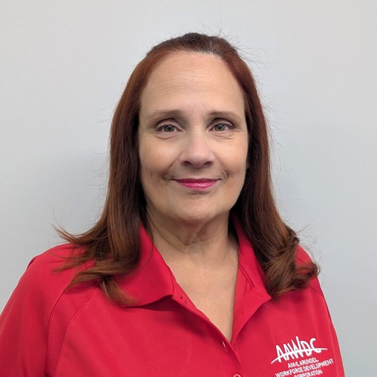 Person smiling in a red AAWDC polo shirt against a plain light background.