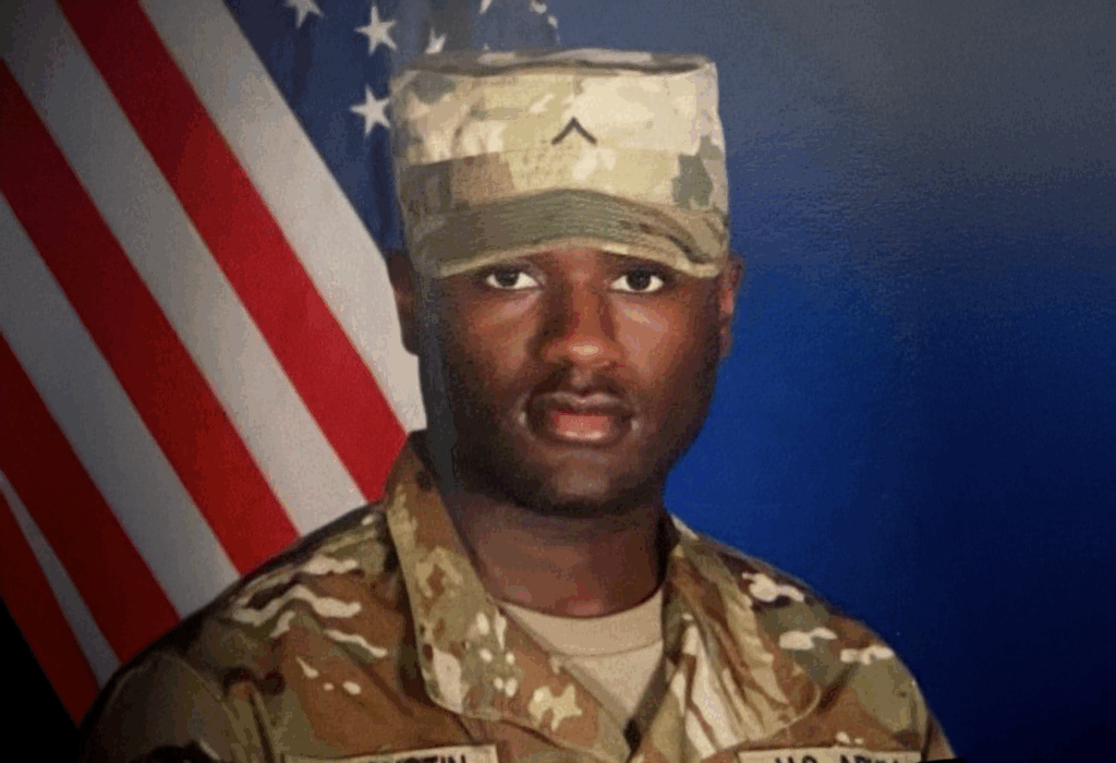 Person in military uniform posing for a portrait in front of an American flag.