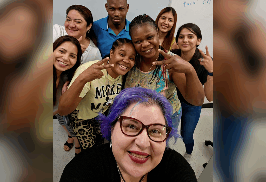Group of people smiling and posing for a selfie in a classroom setting.